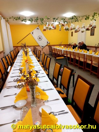A feldíszített terem megterített asztalokkal várja a vendégeket.